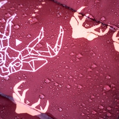 tecido impermeável vermelho escuro com padrão de veados geométricos e gotas de água