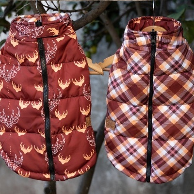 Dois casacos acolchoados para cães com padrões distintos pendurados em cabides de madeira