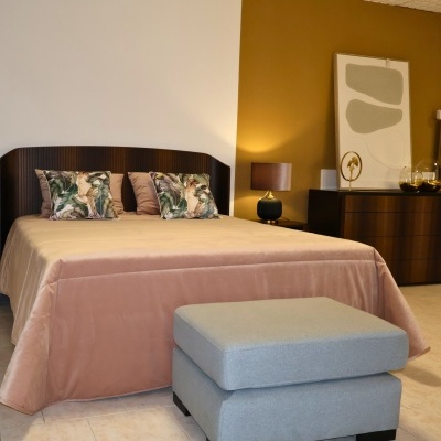 Quarto com cama de madeira escura e almofadas decorativas com estampado de folhas e pássaros