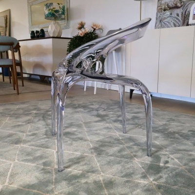 Cadeira acrílica transparente sobre tapete verde claro com padrão geométrico