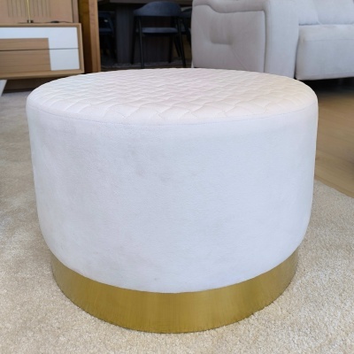 Pufe redondo branco com base dourada em ambiente interior
