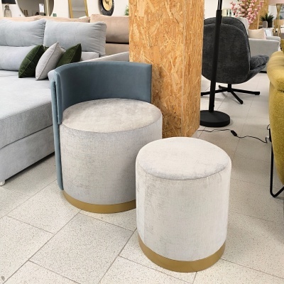 Dois pufes redondos em tecido cinza claro com base dourada, um com encosto azul-acinzentado, em sala com chão bege.