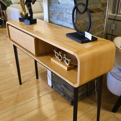 Aparador de madeira clara arredondado com pernas metálicas pretas e decoração