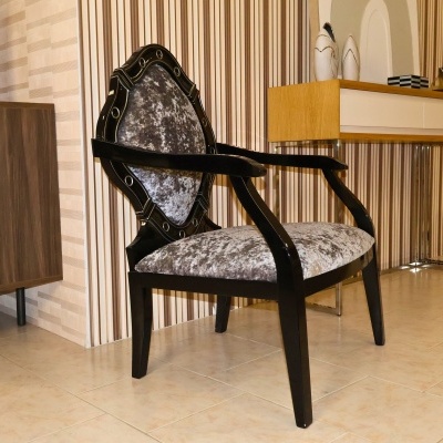 Cadeira de braços preta com estofos cinza em sala com papel de parede listrado