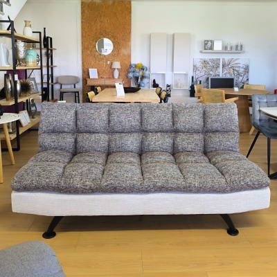 Sofá cinzento com base bege e pernas pretas em sala de exposição