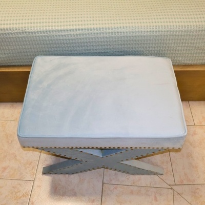 Banco retangular azul claro com almofada aveludada e base cruzada com tachas