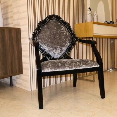 Cadeira preta com estofado cinza aveludado num ambiente interior com móveis de madeira