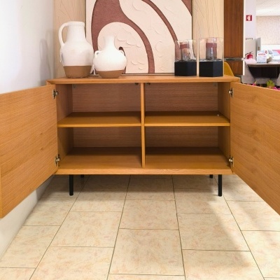 Aparador de madeira clara com dois jarros e duas lanternas em cima.