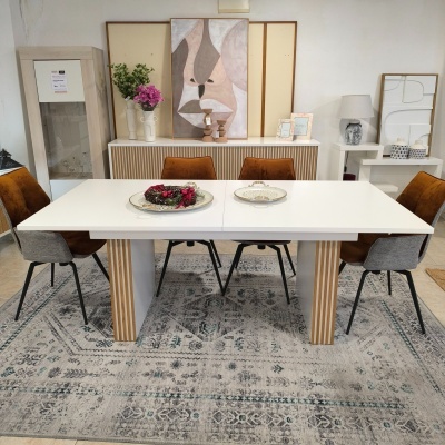 Mesa de jantar branca com cadeiras castanhas e tapete cinza numa sala decorada moderna.