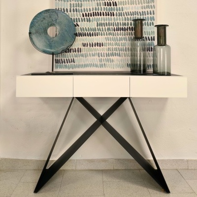 Aparador branco com estrutura preta e decoração de vasos e escultura em ambiente interior.