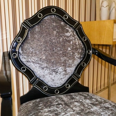 Cadeira preta com estofado cinza aveludado e detalhes circulares na moldura