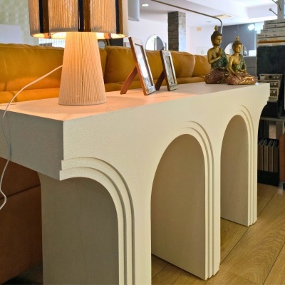 Mesa de apoio branca com três arcos, lâmpada, molduras de fotos e estátuas de Buda sobre a mesa