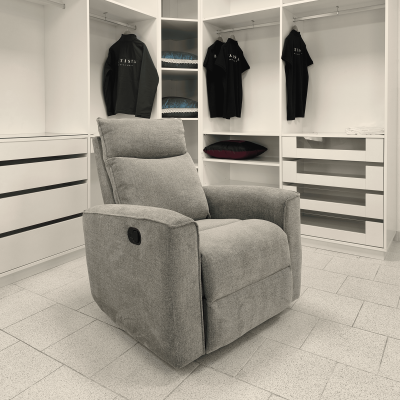 Poltrona reclinável cinza em ambiente branco com armários e camisolas pretas