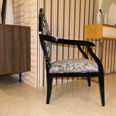 Cadeira de madeira preta com estofos cinzentos num quarto com papel de parede às riscas e móveis