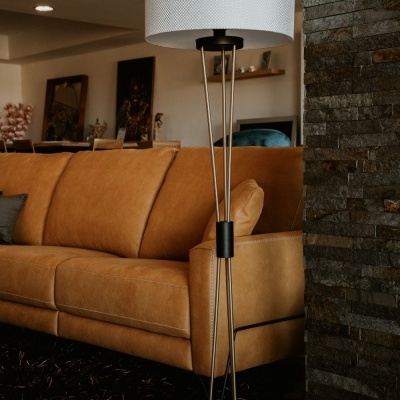 Candeeiro de pé preto com cúpula branca ao lado de sofá de couro mostarda num interior