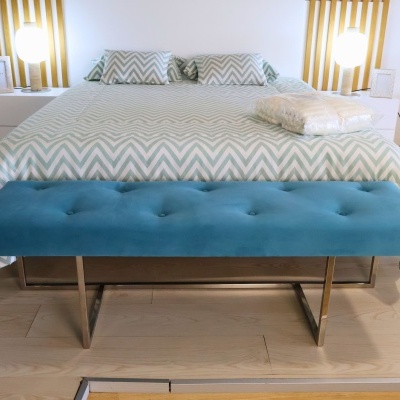 Banco azul estofado com botões em quarto com cama de padrão zigzag cinza e branco