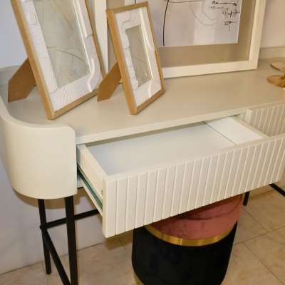 Mesa de apoio branca com gaveta aberta e quadros em cima