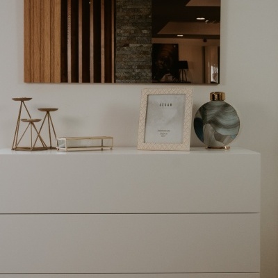 Cómoda branca com objetos decorativos e espelho na parede