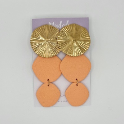 Brincos com metal dourado e pendentes pêssego em cartão lilás.