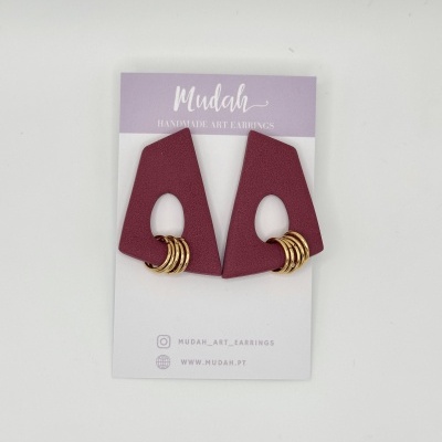 Brincos geométricos roxos com anéis dourados em cartão de apresentação