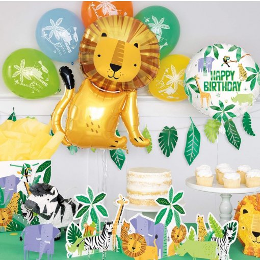 Decoração de festa com balão dourado de leão, balões coloridos com desenhos de animais, texto 'HAPPY BIRTHDAY', figuras de papel de animais e bolo