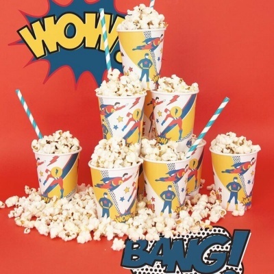 Copos de papel com pipocas e estampas de heróis, fundo vermelho, texto WOW e BANG