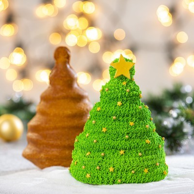 Bolos em forma de árvore de Natal, um verde decorado com estrelas, outro castanho simples ao fundo