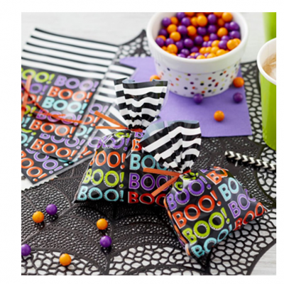 Mini sacos de doces coloridos e recipiente com bolas roxas e laranjas sobre toalha de aranha preta