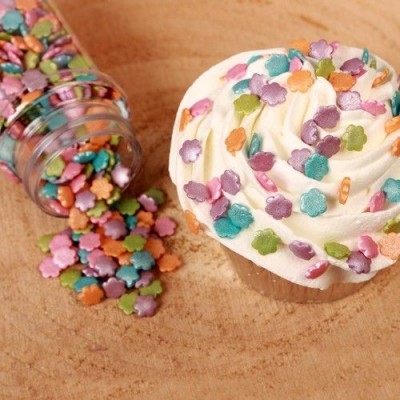 Cupcake com confeitos coloridos em forma de flores e frasco de vidro com confeitos