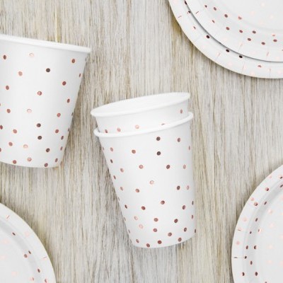 copos e pratos descartáveis brancos com pontos dourados sobre madeira clara