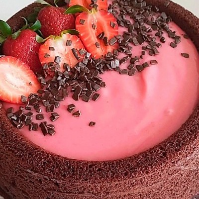 Bolo de chocolate com cobertura rosa, morangos frescos e pedaços de chocolate