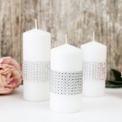 Três velas brancas decorativas com faixas prateadas e flores cor-de-rosa