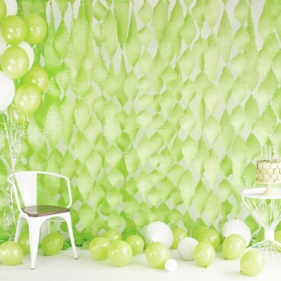 Ambiente decorado com balões verdes e brancos e mobiliário branco com bolo. 