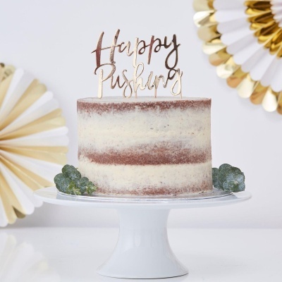 Bolo de aniversário branco e marrom com texto dourado 'Happy Pushing' no topo