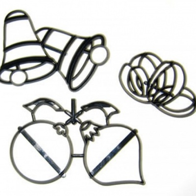 Moldes de metal pretos em formas de sinos e frutas sobre fundo branco