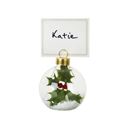 Decoração de mesa com folhas verdes, bagas vermelhas, imitação de neve e cartão com nome Katie