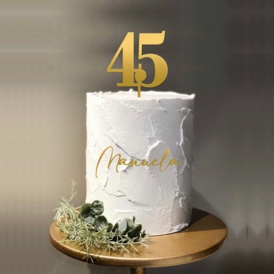 Bolo branco rústico com decoração dourada e folhagem na base