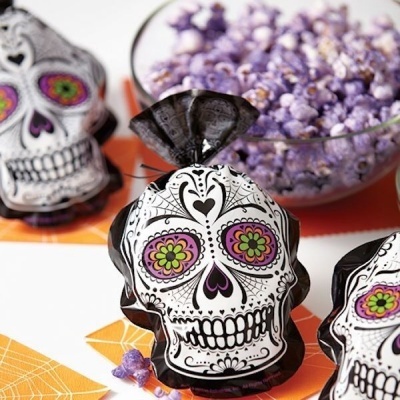 Embalagens em formato de caveira decoradas com padrões florais e corações com flores roxas ao fundo