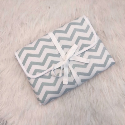 Estojo dobrado com padrão ziguezague cinza e branco com fita branca amarrada