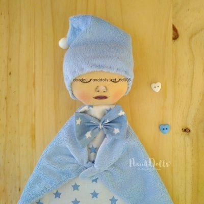 Boneco de pano azul com padrão de estrelas, tecido felpudo, rosto impresso, botões coração, fundo madeira