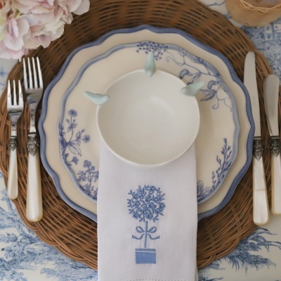 Conjunto de loiça floral azul e branco com talheres e guardanapo bordado