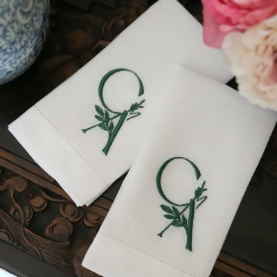 Duas toalhas de linho brancas bordadas com letras e folhas verdes