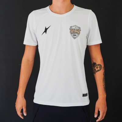 T-shirt branca com símbolo preto e brasão ZELAS SURF usada por pessoa com tatuagem