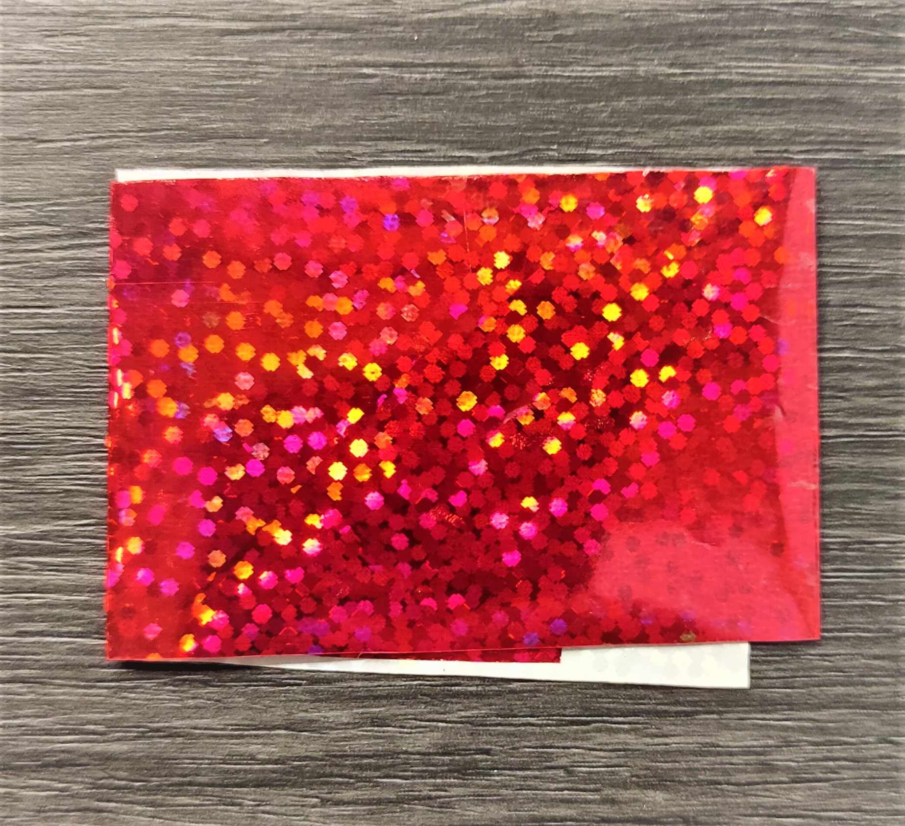 pacote pequeno holográfico vermelho sobre madeira cinzenta