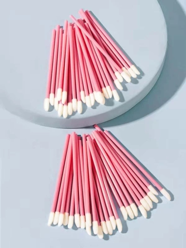 Aplicadores de maquilhagem rosa com pontas brancas sobre superfície clara