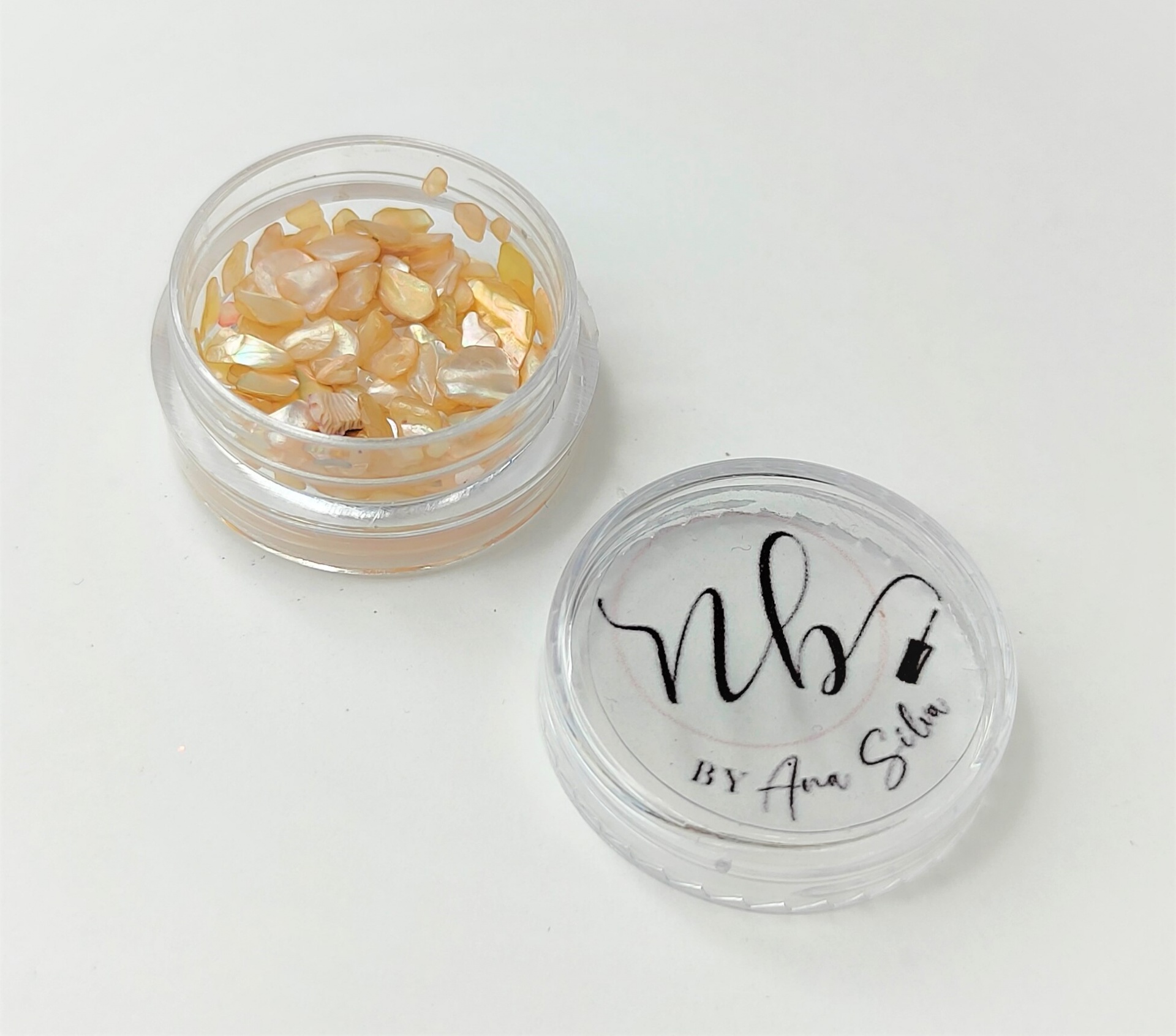 Pote transparente com fragmentos bege e dourados e tampa com texto nb BY Ana Silva