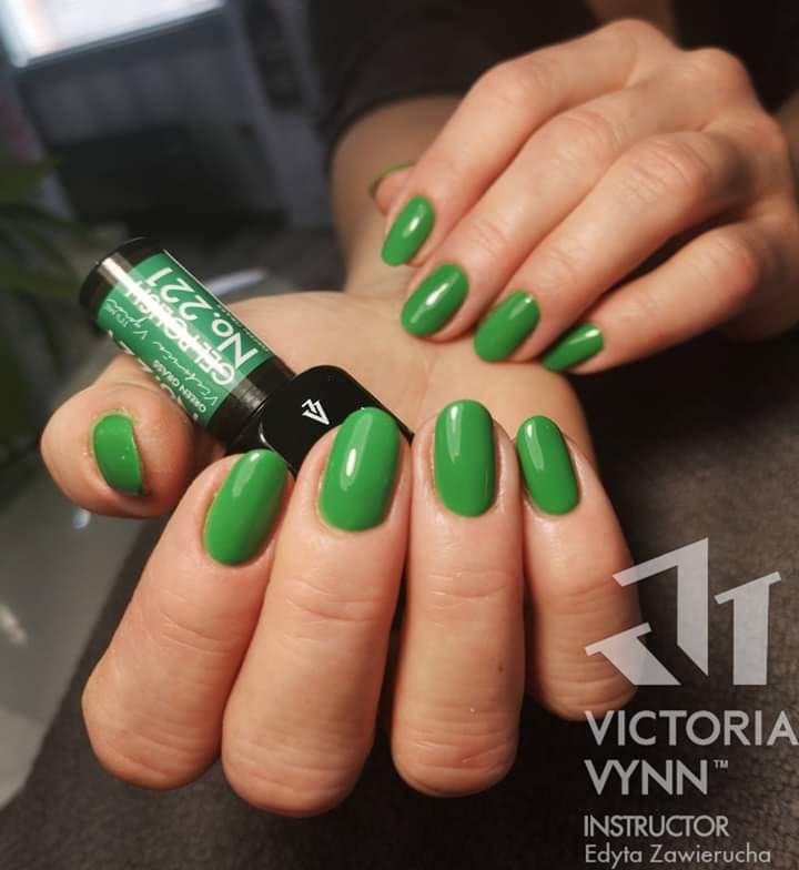 Unhas pintadas de verde brilhante e frasco de verniz Victoria Vynn número 221