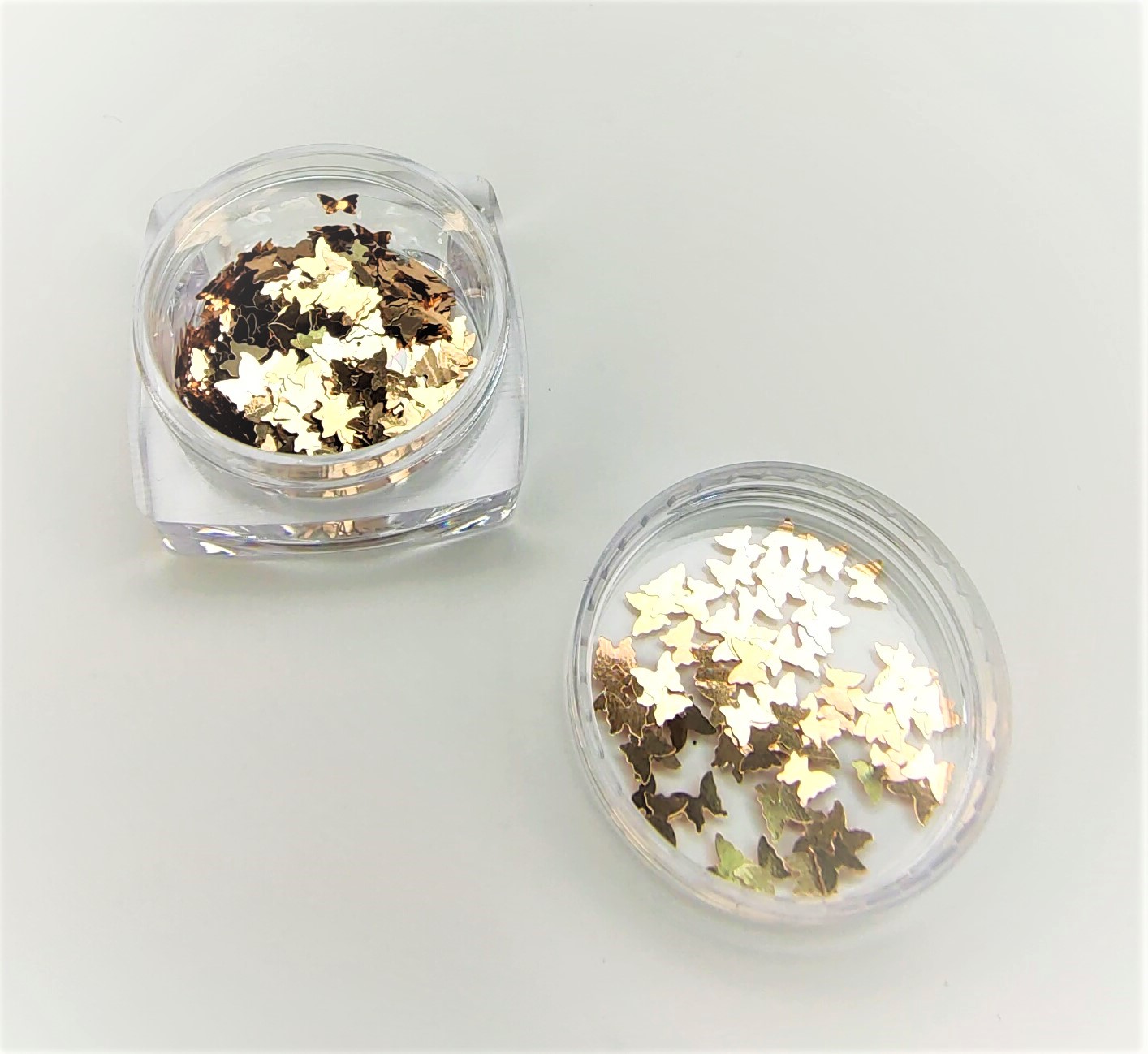 Dois recipientes transparentes com adesivos metálicos dourados e prateados em forma de folhas.