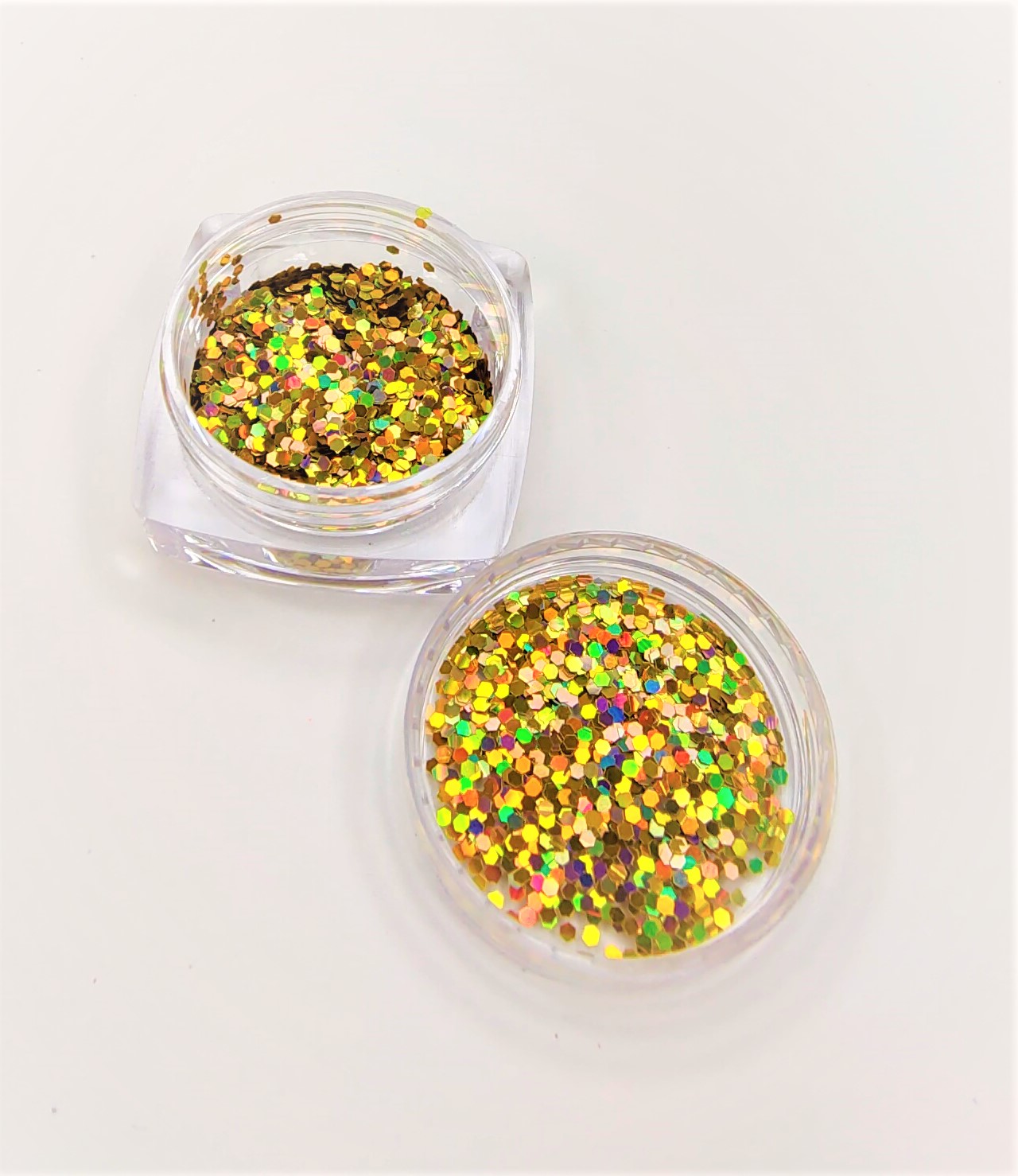 Dois frascos transparentes com purpurina dourada holográfica sobre fundo branco