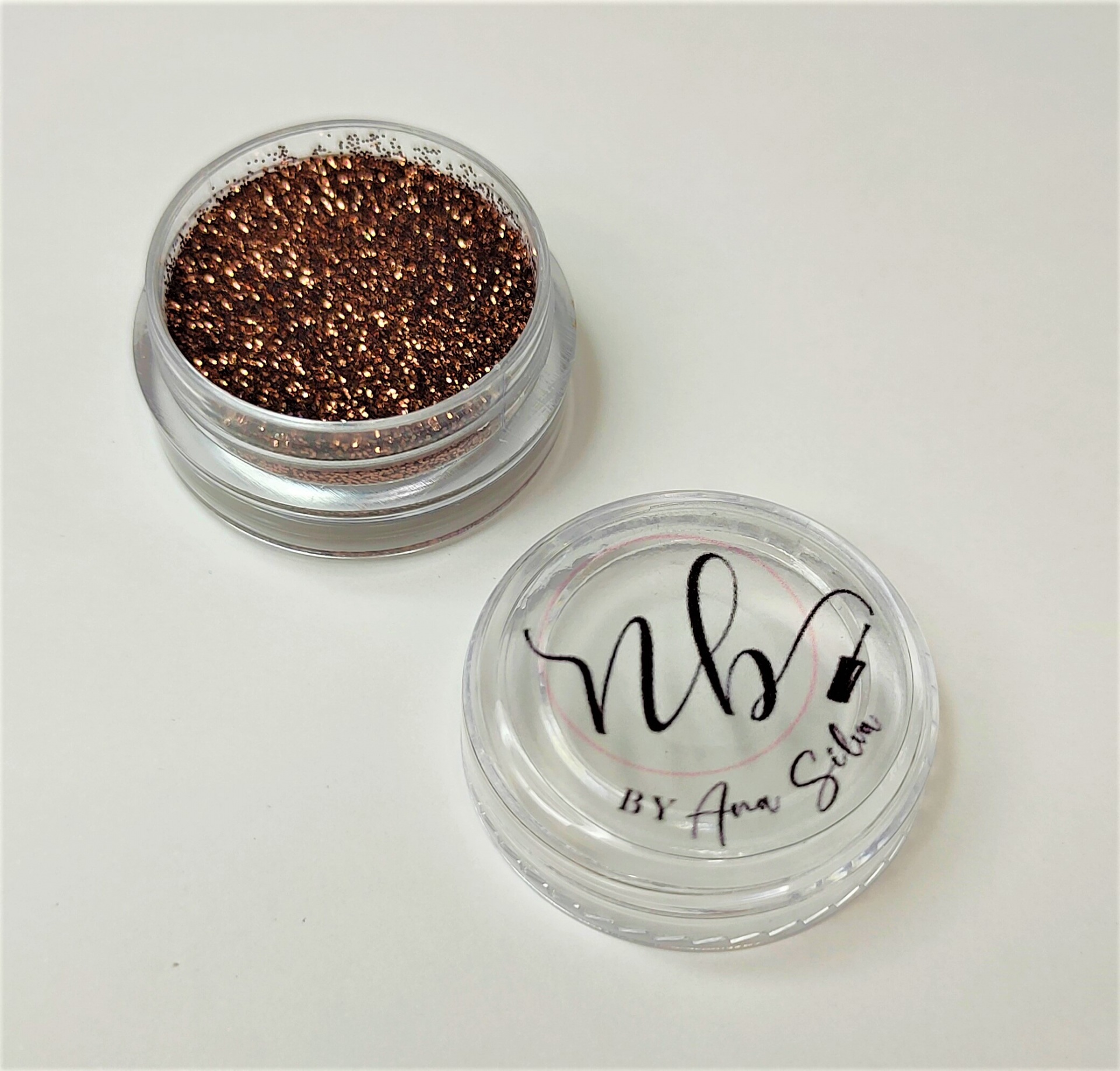Pó solto glitter dourado em recipiente plástico com tampa transparente e texto nb! BY Ana Silva